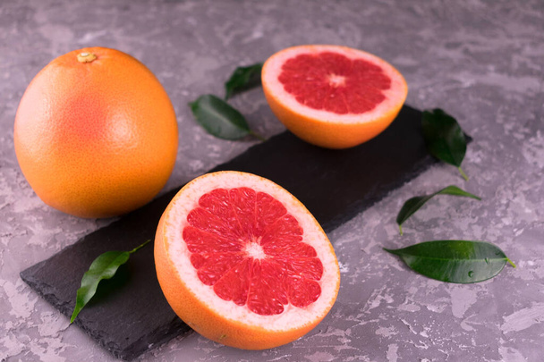 Grapefruit- und Grapefruitkeile auf grauem Hintergrund. Nahaufnahme. - Foto, Bild