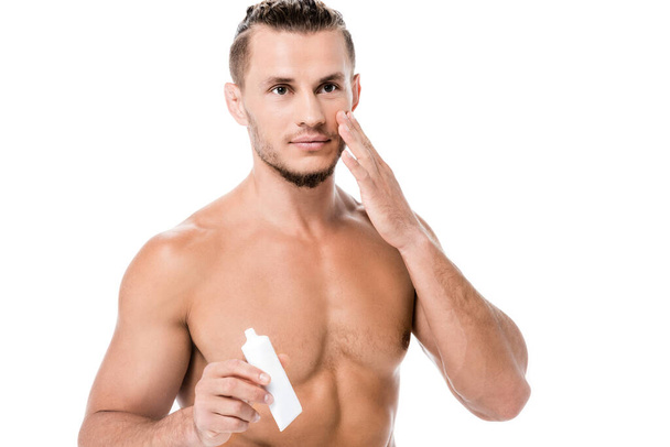sexy shirtless man applying face cream isolated on white - Foto, Imagen