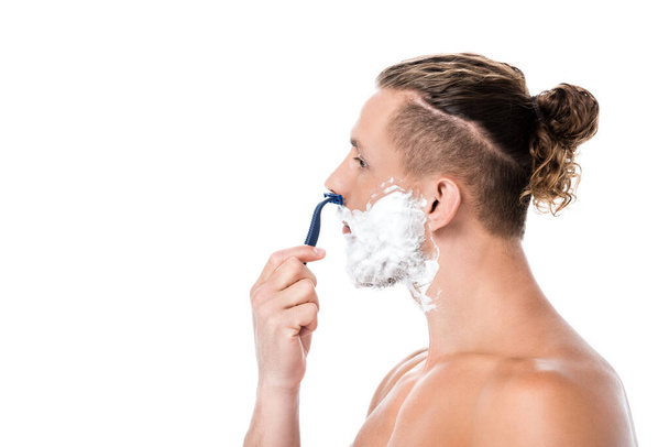 side view of sexy shirtless man with foam on face shaving isolated on white - Fotó, kép