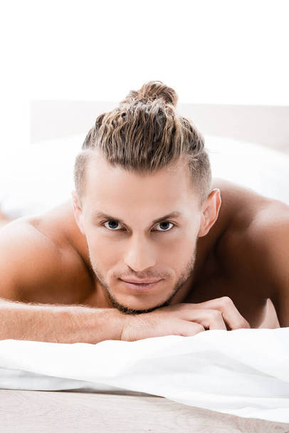 sexy uomo senza maglietta posa a letto isolato su bianco - Foto, immagini