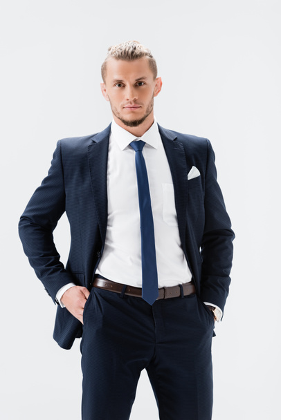 young businessman in suit posing with hands in pockets isolated on white - 写真・画像