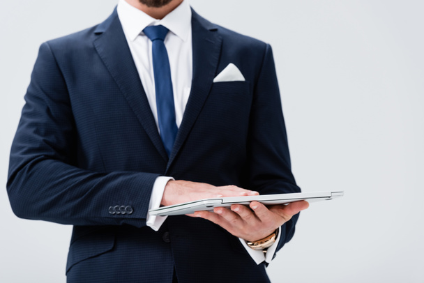 abgeschnittene Ansicht des jungen Geschäftsmannes im Anzug mit Laptop isoliert auf weiß - Foto, Bild