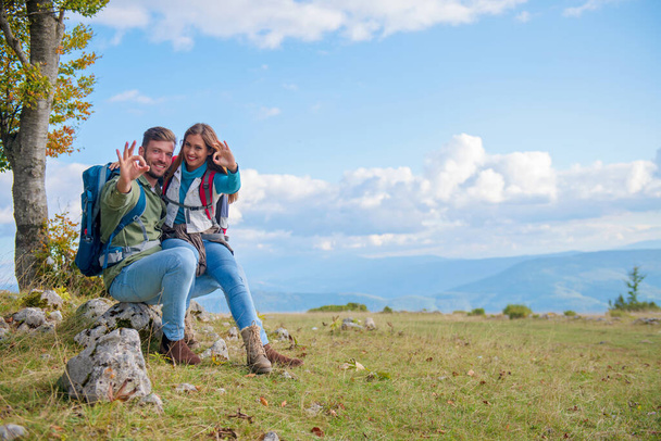 Couple Sitting On A Rock Resting During Hike and showing sign great with hands. - Valokuva, kuva