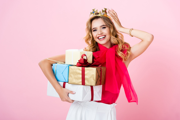 elegant happy woman in crown with gifts on pink background - Photo, Image
