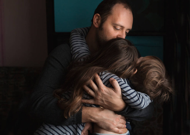 Father hugging daughter and son at home - Foto, afbeelding