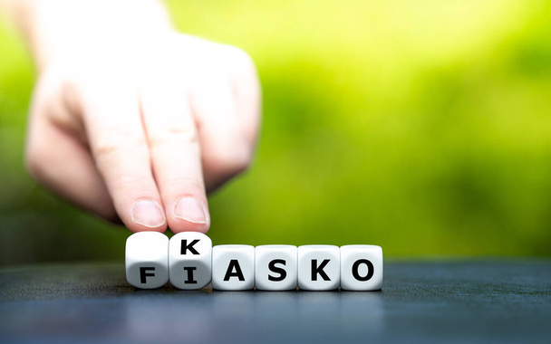 Hand draait dobbelstenen en verandert de Duitse uitdrukking "Fiasko" (fiasco) in "Kasko" (dekking). - Foto, afbeelding