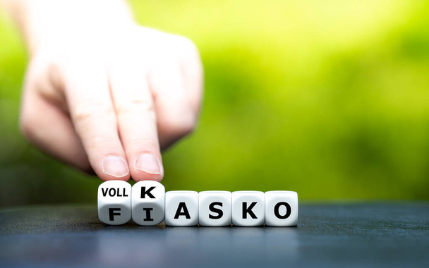 Hand draait dobbelstenen en verandert de Duitse uitdrukking "Fiasko" (fiasco) in "Vollkasko" (uitgebreide dekking). - Foto, afbeelding