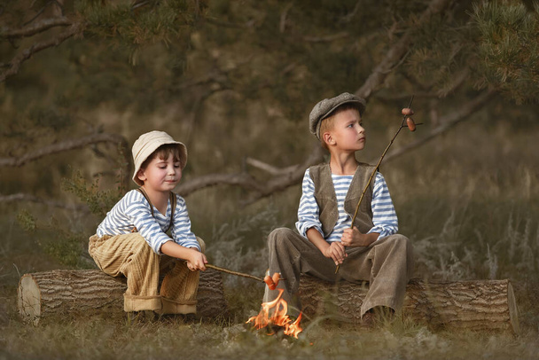 Boys fry sausages in the woods at the stake on a summer evening - Foto, imagen