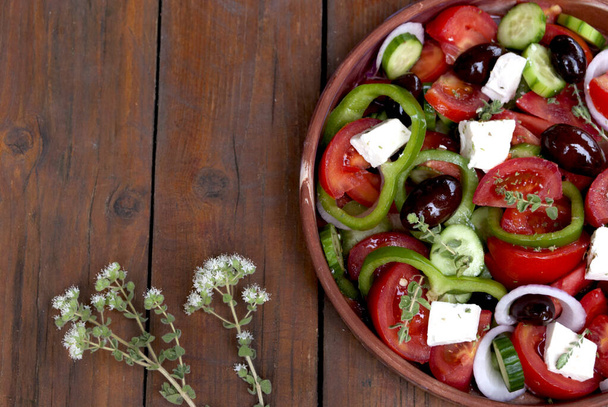 Traditional greek salad in ceramic plate on stripped woven fabric  - Foto, imagen