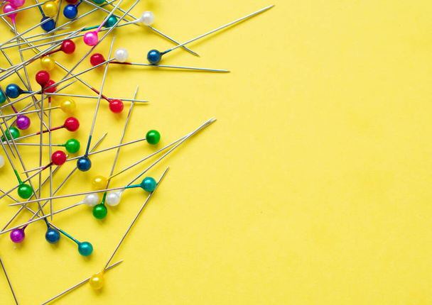 Some colorful pins over a bright yellow background with copy space on the right side of the image - Fotografie, Obrázek