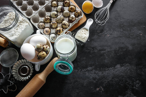 ingredients for baking eggs, flour, milk and utensils on a black background - Foto, Imagem