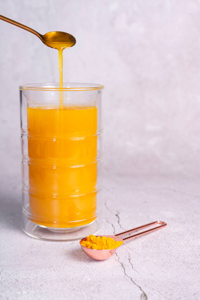 una bebida caliente de cúrcuma, leche dorada. especia sana natural, en un vaso termo alto  - Foto, imagen