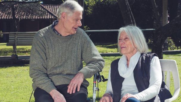 Starszy mężczyzna i kobieta nawiązujący znajomość w ogrodzie szpitalnym. Zwolniony ruch. - Zdjęcie, obraz