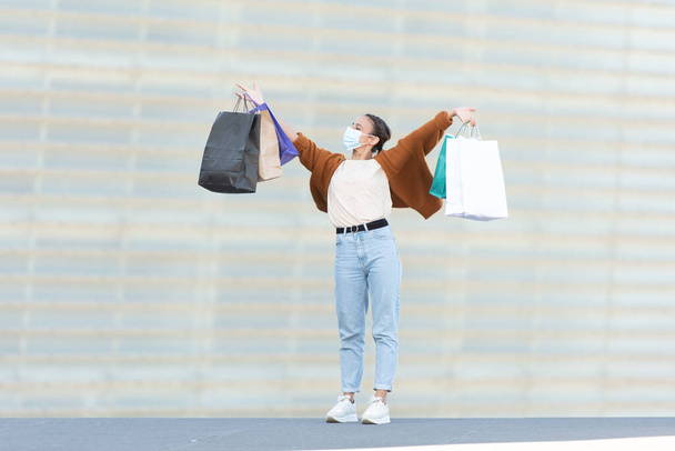 Shopping pendant la pandémie de coronavirus concept. Une jeune femme heureuse et fière tenant ses sacs à provisions. - Photo, image