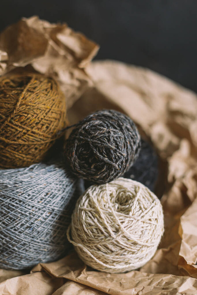Cozy balls of yarn for hand knitting with dry oak leaf on a dark background. Autumn background for handmade and slow homelife. Selective focus. - Photo, Image