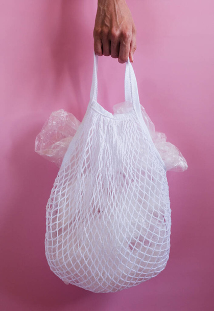 Plastic bags in a string bag on pink background. - Foto, Bild