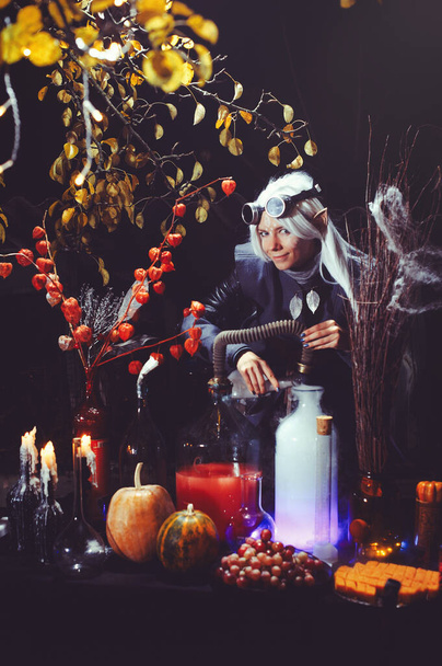 Elfo di Halloween con magia magica nella foresta oscura. Bella giovane donna con un cappello e un costume da elfo che tiene chimica magica. Design artistico di Halloween - Foto, immagini