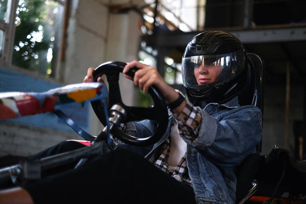 Frau in einem Sportwagen auf Kartfahren. schönes Mädchen mit Helm am Steuer eines Autos - Foto, Bild