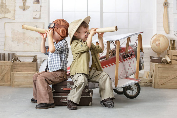 Two little boys imagine themselves as a pilot and a tourist and look down the tube near the plane - Fotografie, Obrázek