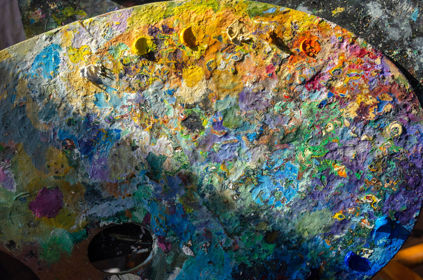 Foto stock de uma paleta de pintores com cores de óleo misturadas e não misturadas com luz solar - Foto, Imagem