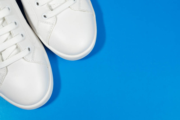 White sneakers isolated on blue background. - Photo, Image
