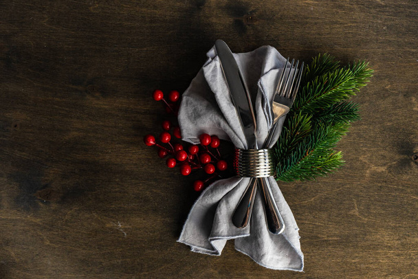 Set de cubiertos navideños con servilleta y decoración navideña en mesa de madera - Foto, imagen