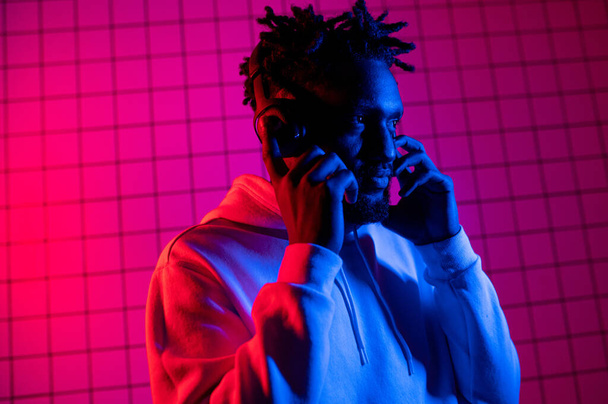  black man listens to music with headphones and dances. Red blue background - Valokuva, kuva