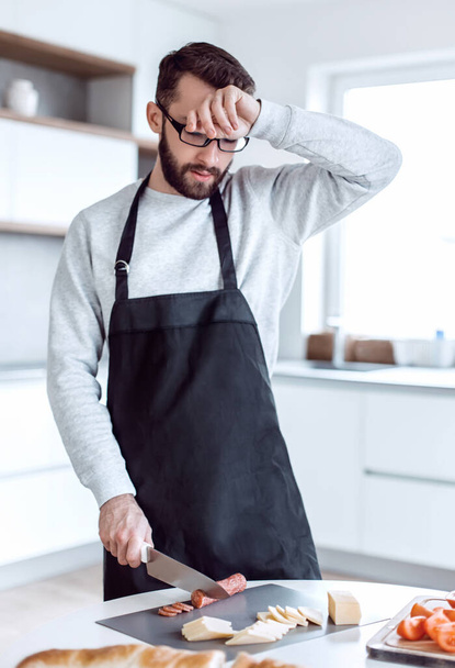 tired man makes sandwiches in his kitchen - Foto, imagen