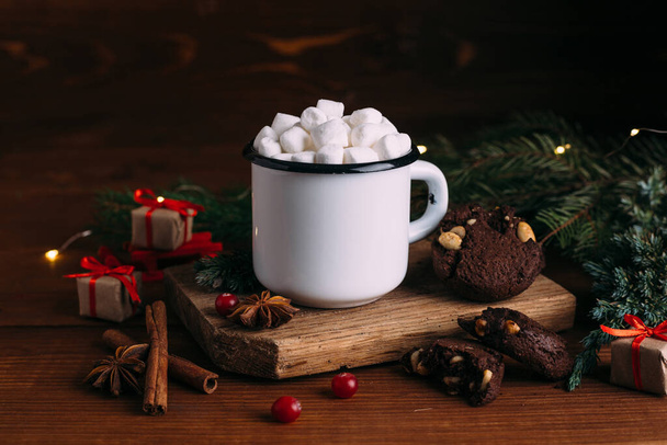 Чашка эмалированного горячего какао или кофе с зефиром и печеньем. Отделения ели и рождественские подарки. - Фото, изображение