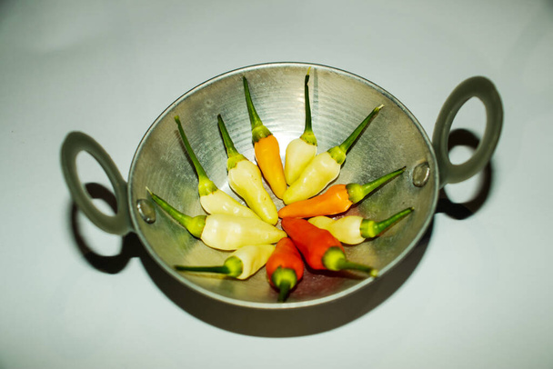 Pentola da cucina con peperoncini bianchi rossi e arancioni nella pianta - Foto, immagini