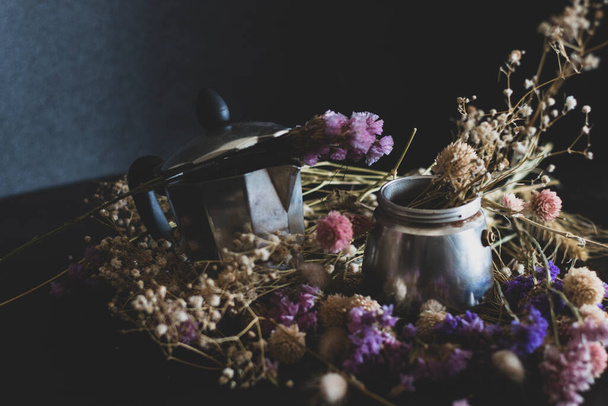 Coffee making concept. Ingredients for making moka coffee. Moka pot with coffee on dark background with a lot of colorful flowers. The coffee is in a vintage aesthetic composition. - Photo, Image