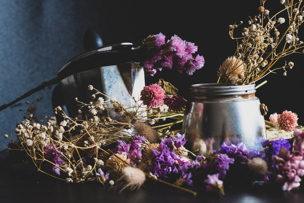 Coffee making concept. Ingredients for making moka coffee. Moka pot with coffee on dark background with a lot of colorful flowers. The coffee is in a vintage aesthetic composition. - Фото, изображение