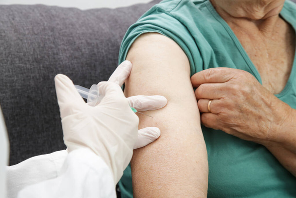 Yaşlı kadın aşı yaptırıyor. Yaşlı bir hastaya grip, grip, zatürree ya da koronavirüs aşısı yapan bir tıp çalışanı. - Fotoğraf, Görsel