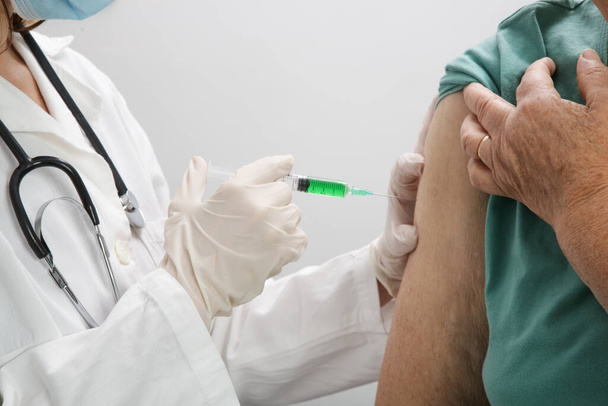 Seniorin erhält Impfung. Medizinisches Personal impft ältere Patienten gegen Grippe, Grippe, Lungenentzündung oder Coronavirus. - Foto, Bild
