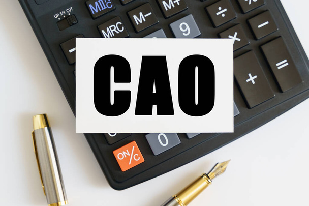 Business and finance concept. On the table there is a pen, a calculator and a business card on which the text is written CAO. CHIEF ACCOUNTING OFFICER - Photo, image