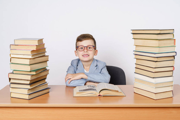 Education concept. A student with glasses sits at a table with books on both sides. - Valokuva, kuva