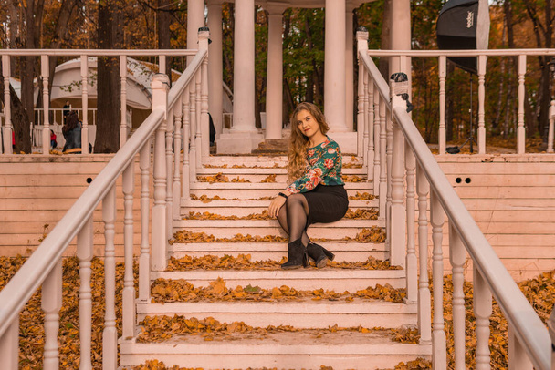 A girl sits on a white staircase in an autumn park in the woods. Beautiful blond - Foto, immagini