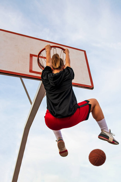 Samice hrají basketbal na pouličním hřišti. Žena streetball hráč dělat slam ponořit do basketbalové hry. - Fotografie, Obrázek
