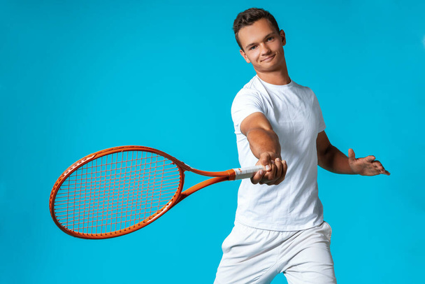 Young man tennis player in sportswear posing against blue background - Фото, зображення