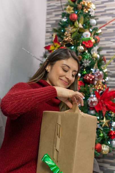 Щаслива жінка відкриває подарунок вдома на Різдво
 - Фото, зображення