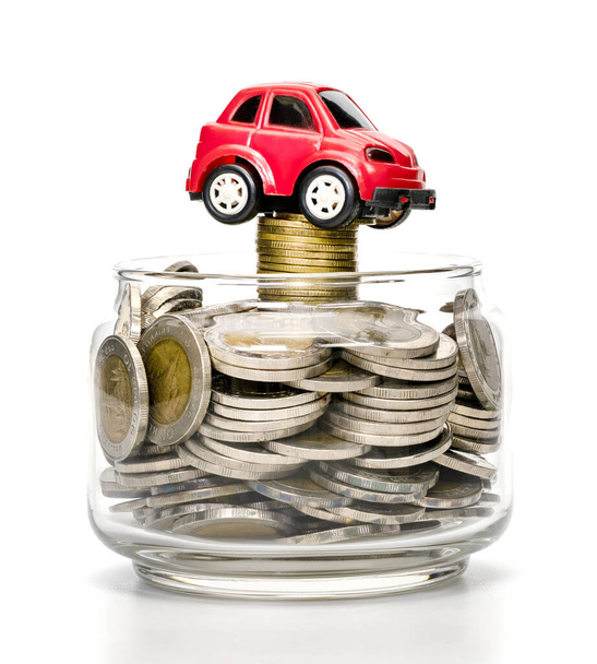 monedas en botella de vidrio y coche sobre fondo blanco, ahorro de negocio y concepto de inversión - Foto, imagen