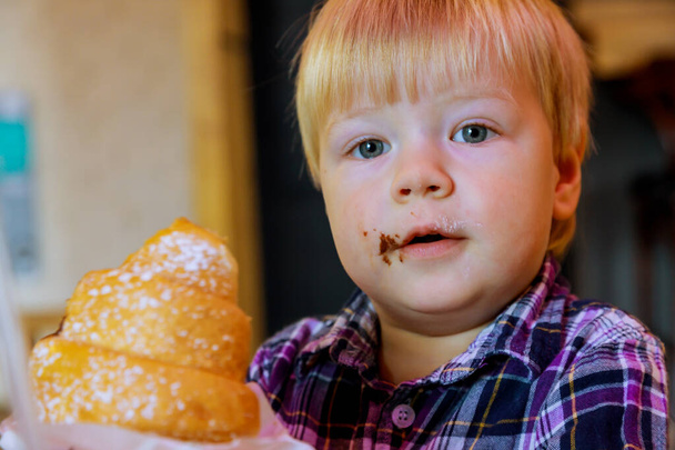 Ontbijt mooie baby gelukkig jongen eten croissant in coffeeshop. - Foto, afbeelding