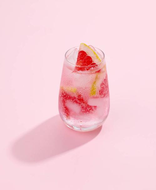 glass of grapefruit soft drink with long shadow on pink background - 写真・画像