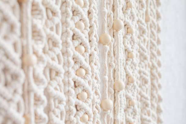 Close-up of hand made macrame texture pattern. Eco friendly modern knitting. Natural decoration concept in the interior. Handmade macrame wall hanging 100% cotton and wooden beads. Soft focus - Valokuva, kuva