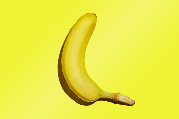 Cały dojrzały banan wyizolowany na żółtym tle gradientowym. - Zdjęcie, obraz