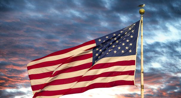 Χρώμα ηλιοβασιλέματος στο φόντο ενός κυματίζει όμορφη αμερικανική σημαία. - Φωτογραφία, εικόνα