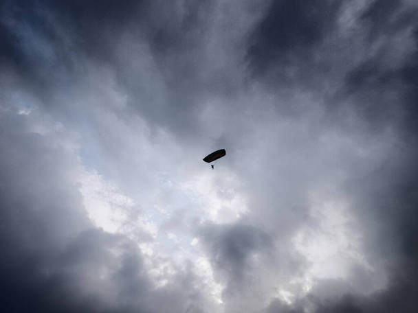 Varjoliito näkyy alla olevasta päivästä mustan pilven taustalla valkoista taivasta vasten - Valokuva, kuva