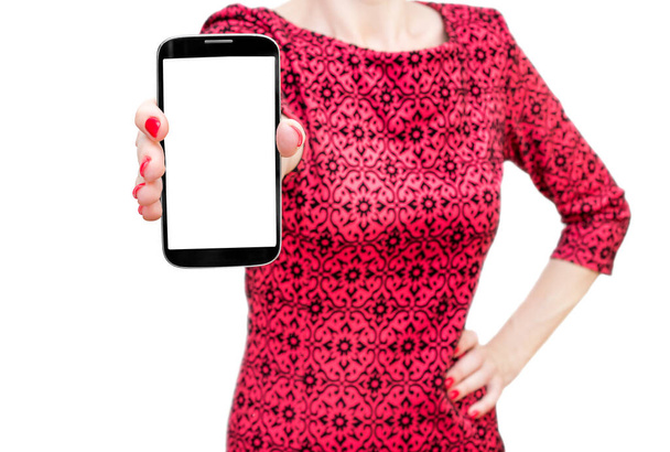Γυναίκα σε κόκκινο φόρεμα κρατώντας smartphone με κενή οθόνη. Απομονωμένα σε λευκό. - Φωτογραφία, εικόνα