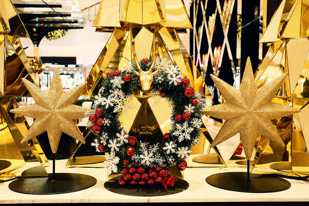 un'elegante corona di Natale decorata con fiocchi di neve e palline rosse è circondata da stelle dorate e albero di Natale - Foto, immagini