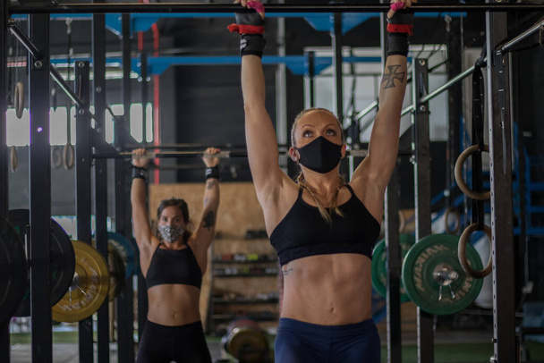 Κορίτσια με μάσκα σε ένα γυμναστήριο που κάνουν προπόνηση Cross - Φωτογραφία, εικόνα